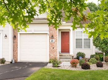 Exterior view of ranch townhome with attached 1-car garage, front sidewalk, and covered, private front entrance